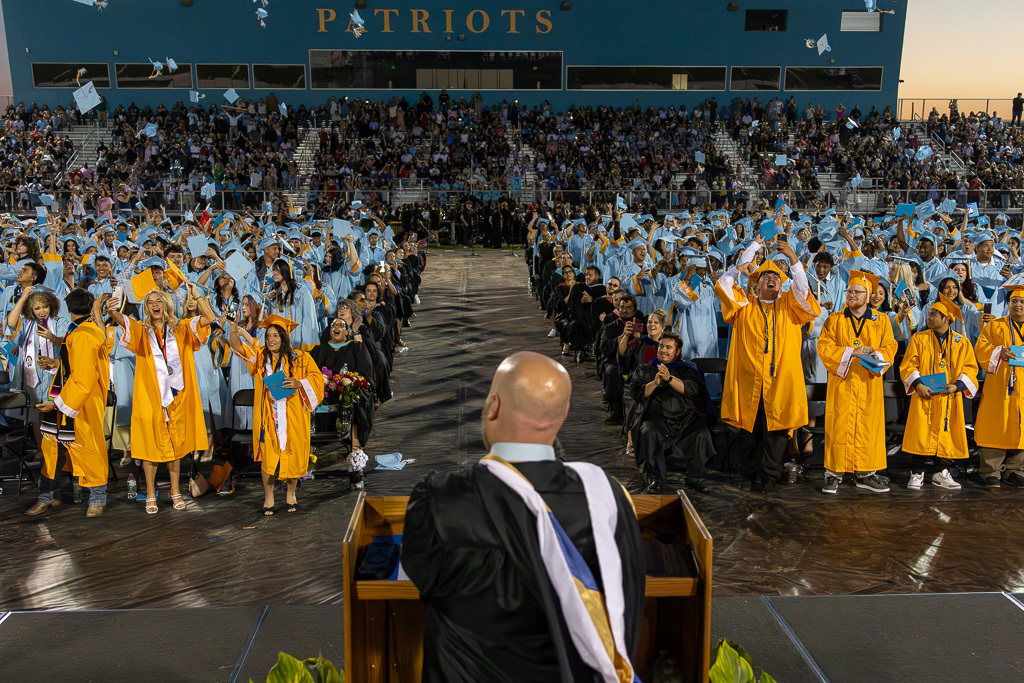 Putnam City West graduates toss their caps and cheer as the Class of 2026 graduation ceremony ends in Patriot Stadium.