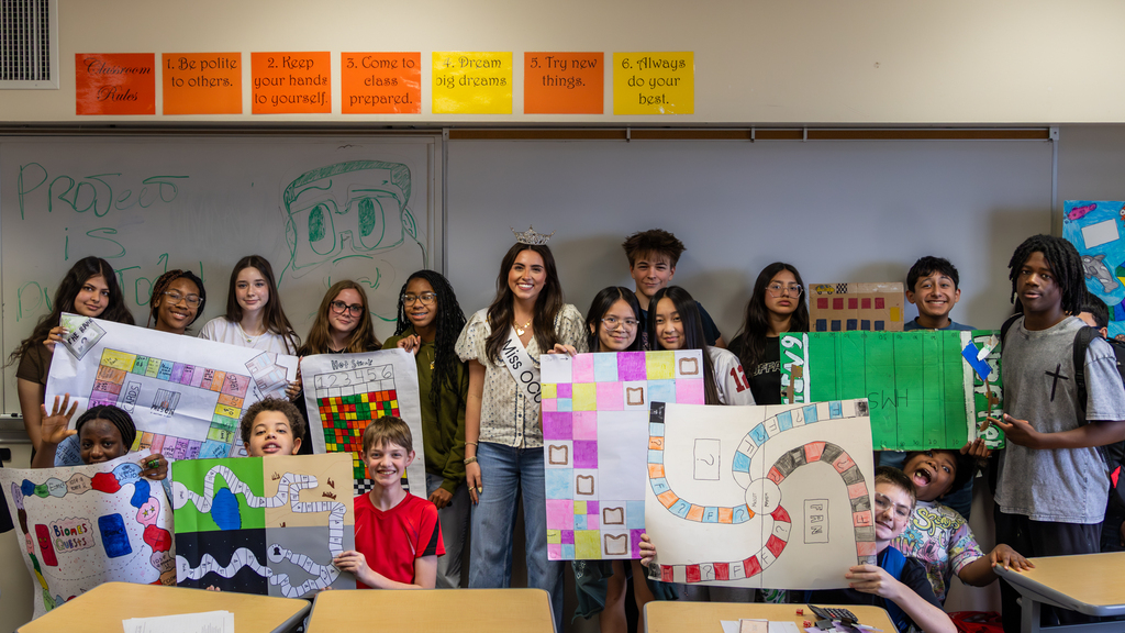 Hefner Middle School students pose with their handmade math board games and Miss Oklahoma during a classroom visit.