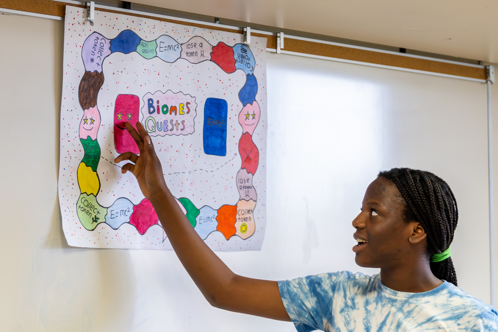 A Hefner Middle School student points to a handmade board game called “Biomes Quest” during a class presentation.
