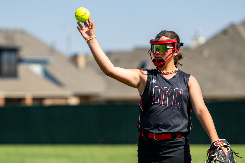 A student raises a softball before making a throw during Hefner Middle School tryouts.
