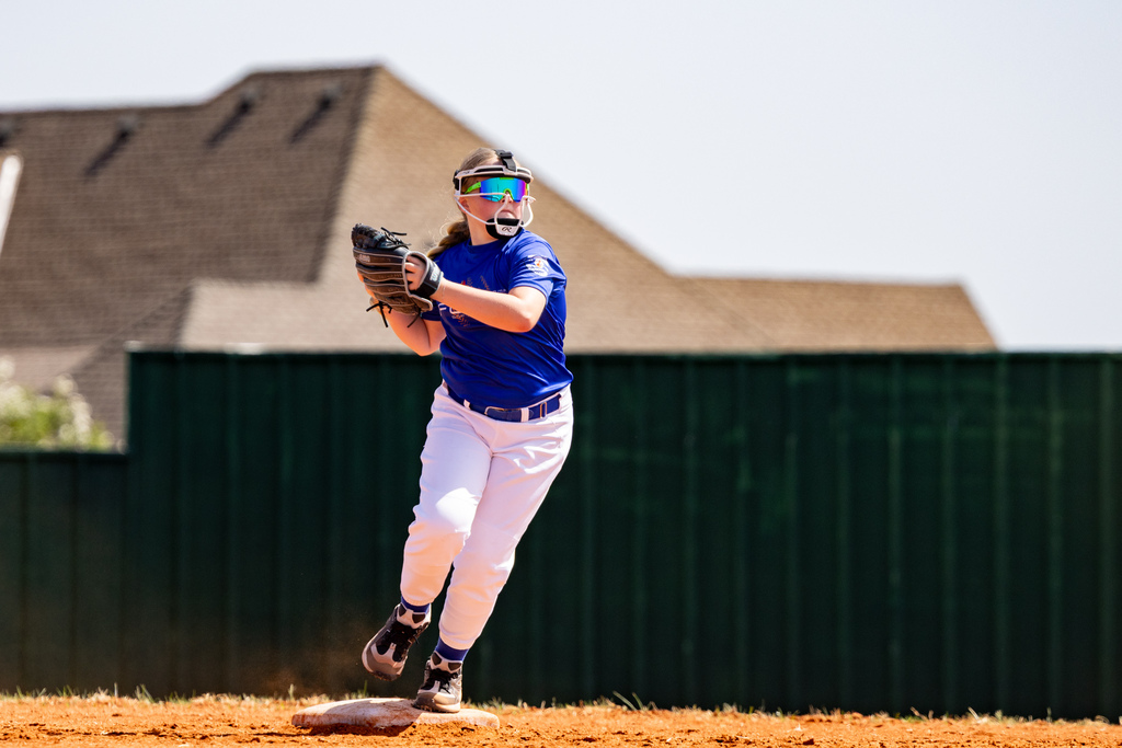 A student pivots on a base with the softball secured in her glove.