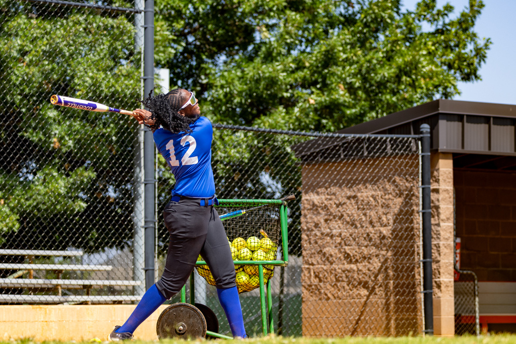 A student follows through after a swing during batting practice.