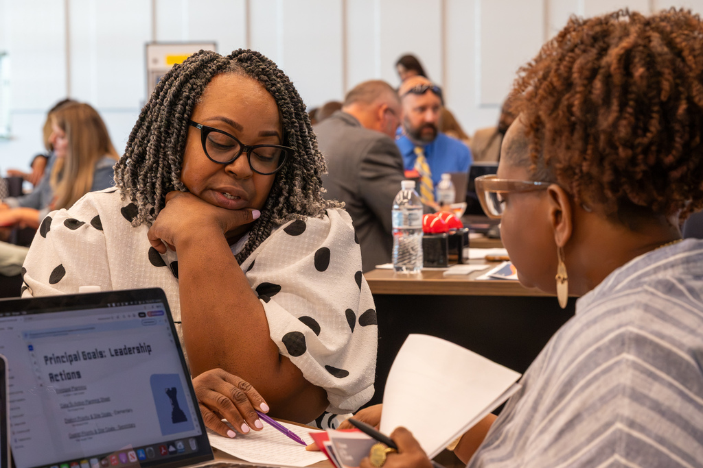 Two administrators discuss a worksheet during a small-group activity.