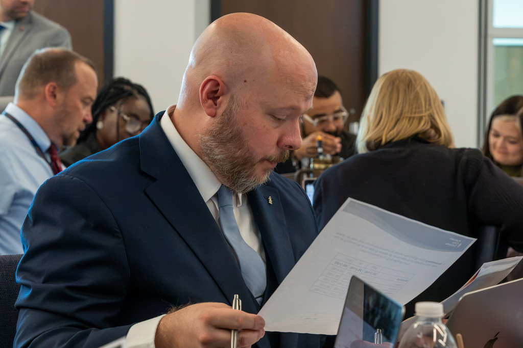An administrator reads a printed worksheet and takes notes during the workshop.
