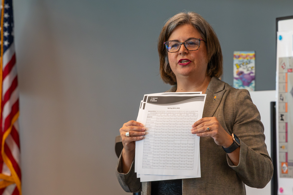 A presenter holds up printed materials while speaking during the All-Admin Workshop.