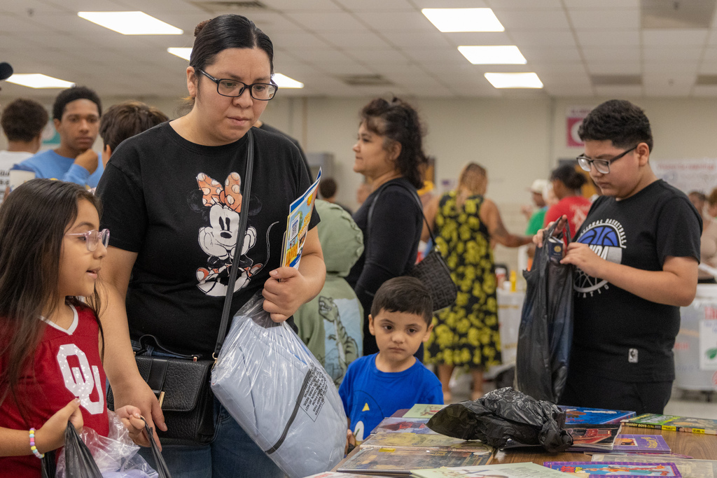 A family looks through books and school materials displayed on a table inside Western Oaks Middle School.