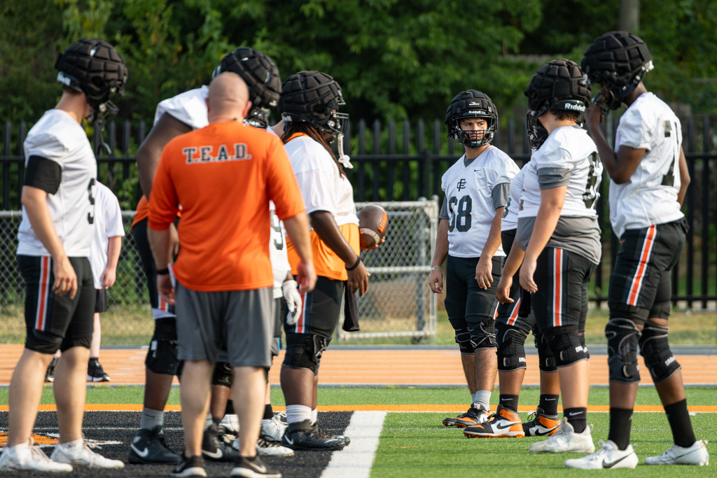 Putnam City High football players gather around coaches between drills during summer camp.
