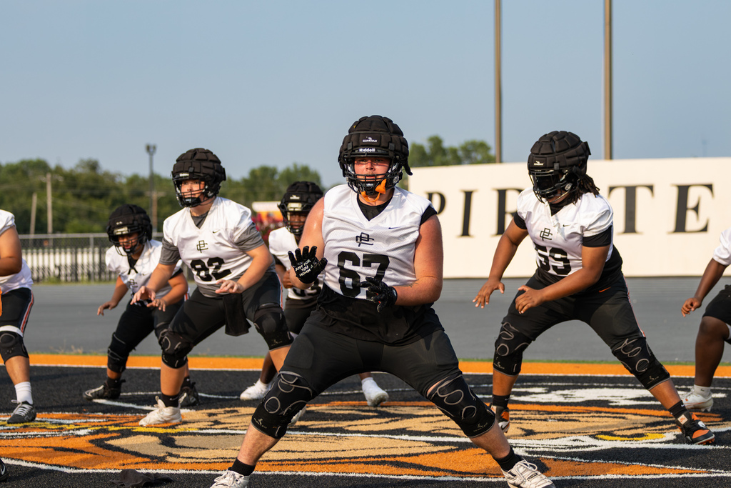 Putnam City High offensive linemen work through a stance drill on the midfield logo.