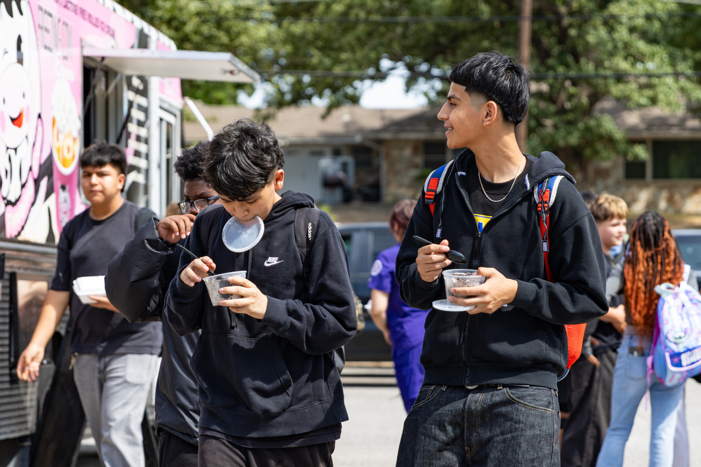 Putnam City West students stand near a food truck eating and talking during the Back to School Bash.
