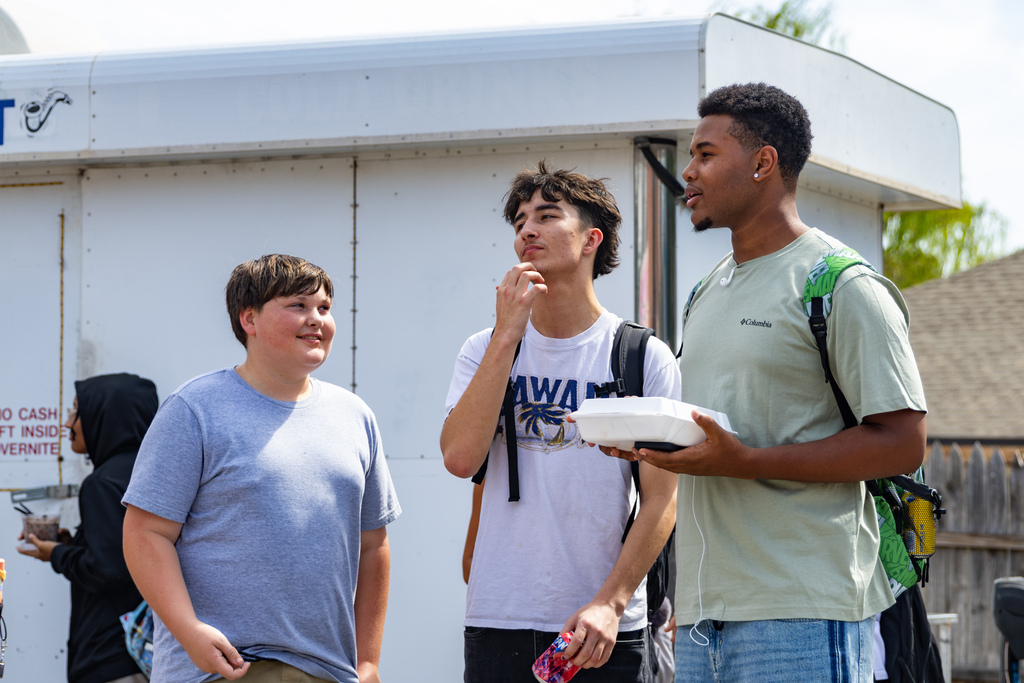 Three Putnam City West students visit with each other while holding food from the lunchtime Back to School Bash.