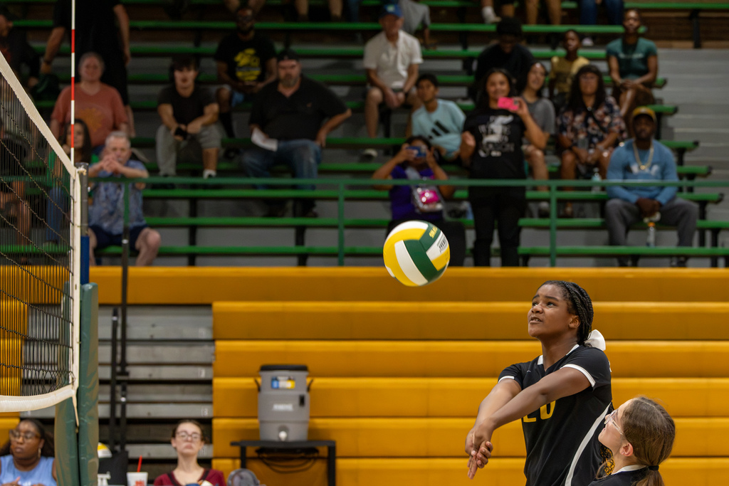 A Cooper Middle School volleyball player passes the ball near the net while a teammate watches from beside her.