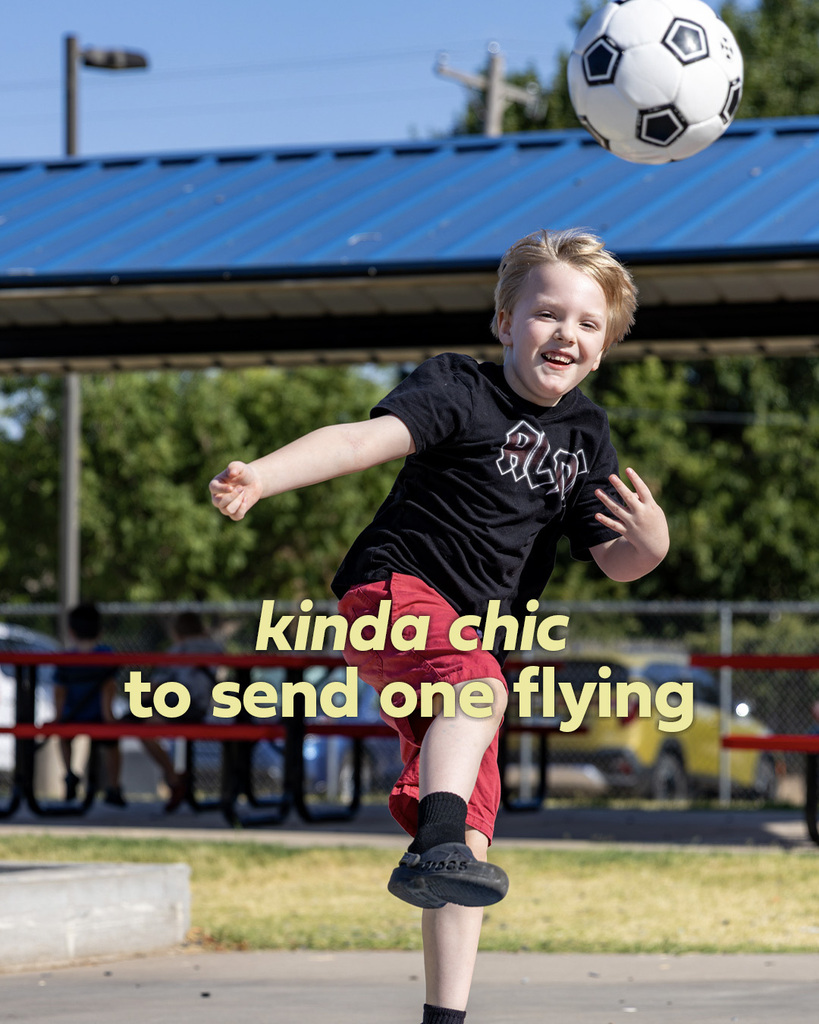 A smiling student kicks a soccer ball across the grass, captured with his leg extended through the kick. Text reads, “kinda chic to send one flying.”