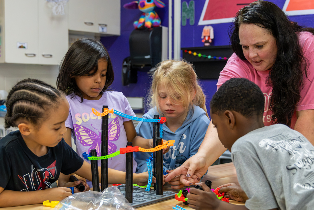 Mrs. Wade helps a group of Rollingwood Elementary students build and adjust a colorful roller coaster track during STEM class.