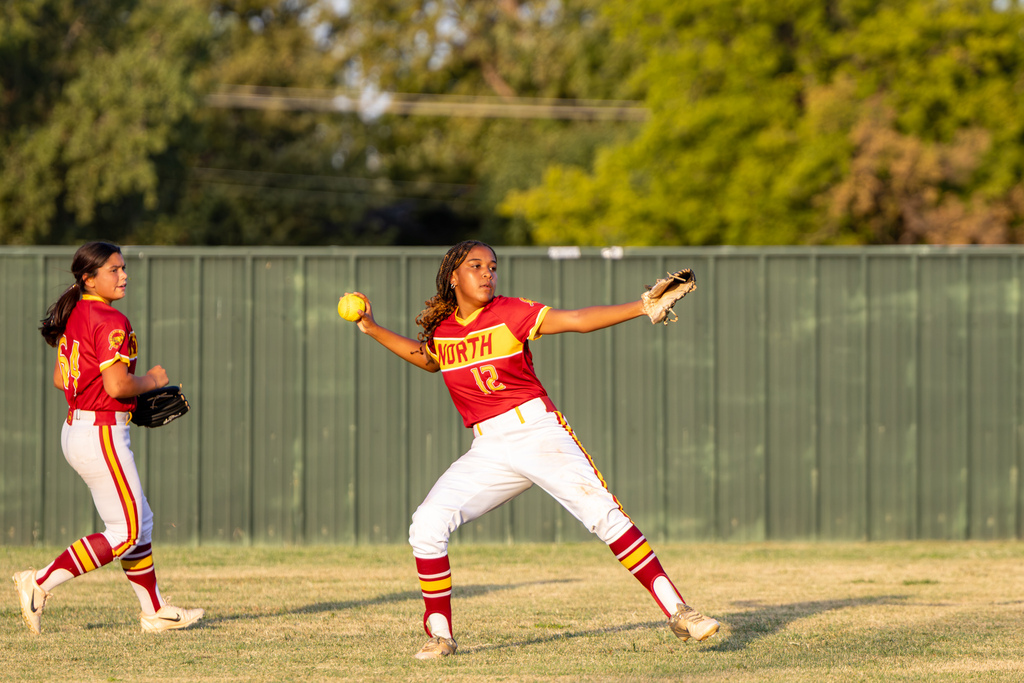 A PC North player prepares to throw the softball from the outfield while a teammate moves behind her.