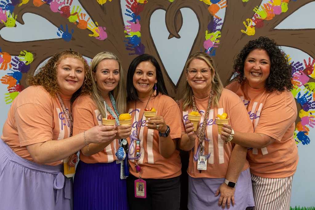 5 teachers hold up fruit cups together