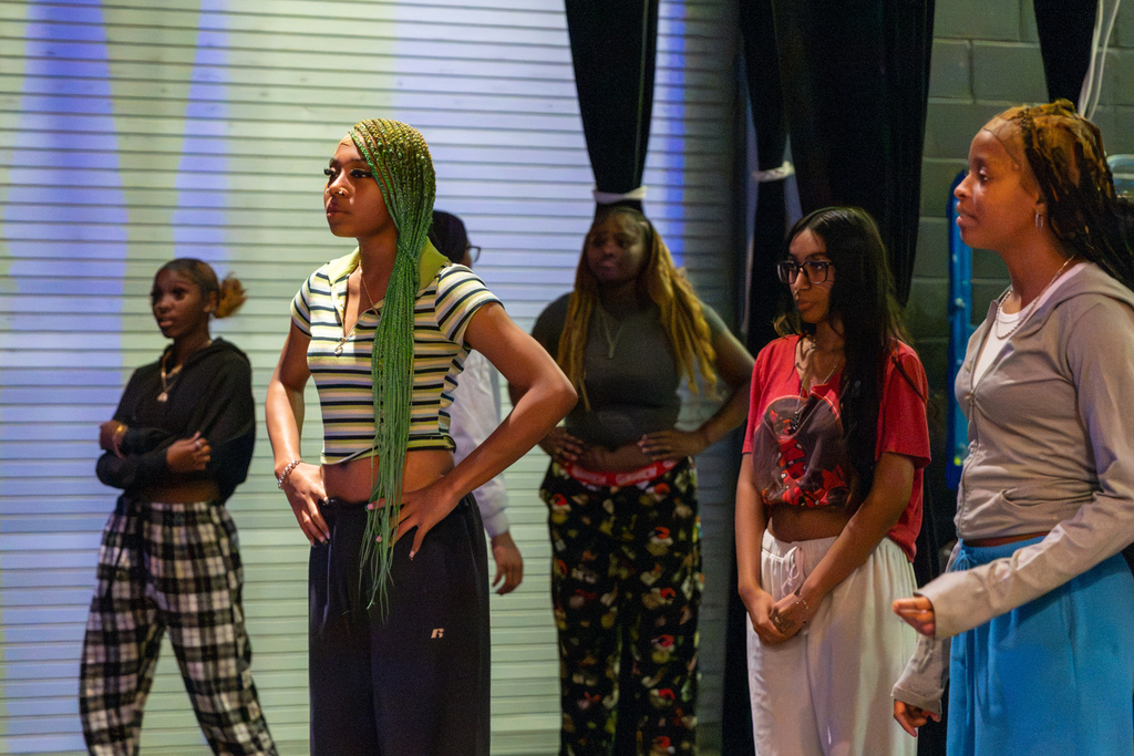 PC High dance students stand onstage listening and watching as they prepare to practice choreography.