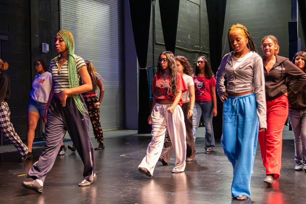 A group of PC High dance students moves across the stage together while practicing choreography.
