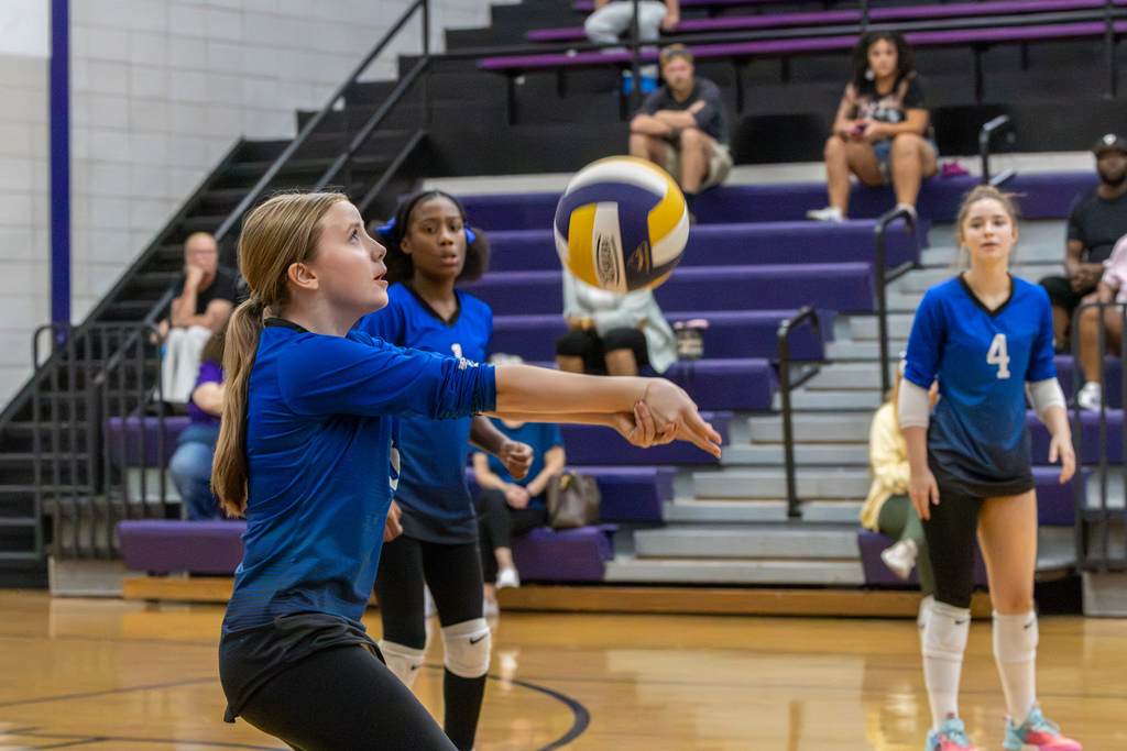 A Hefner Middle School player makes a forearm pass while two teammates watch the ball behind her.