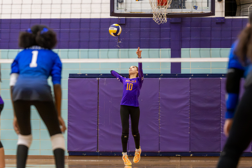Mayfield player number 10 serves the volleyball from the back court as Hefner players prepare to receive.