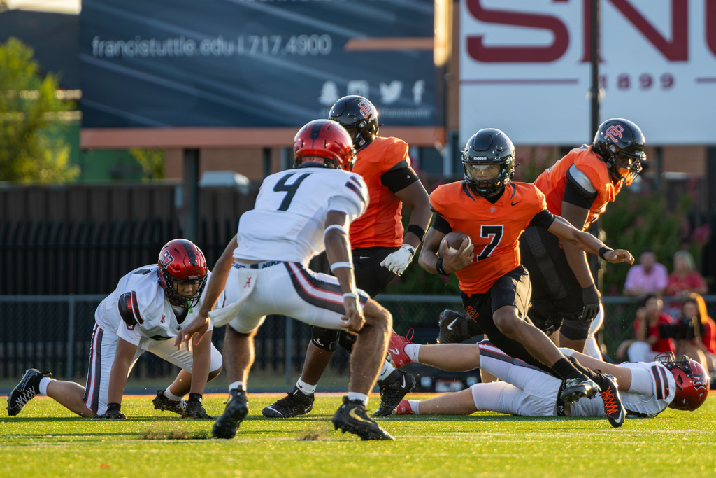 Putnam City High No. 7 carries the football toward two approaching Yukon defenders.