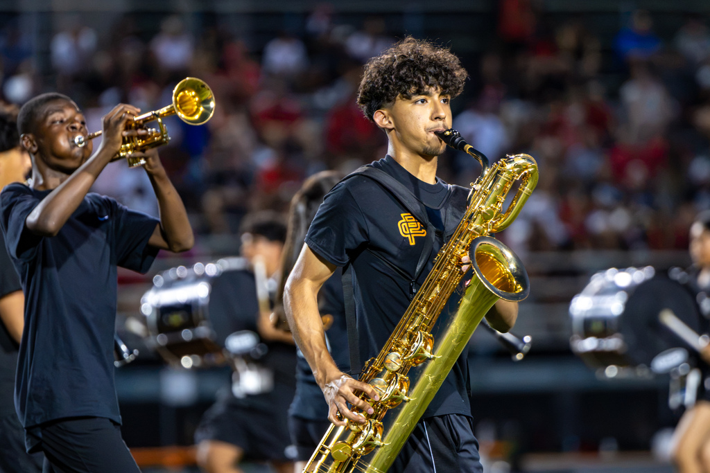Putnam City High band members play baritone saxophone and trumpet in the stands during the football game.