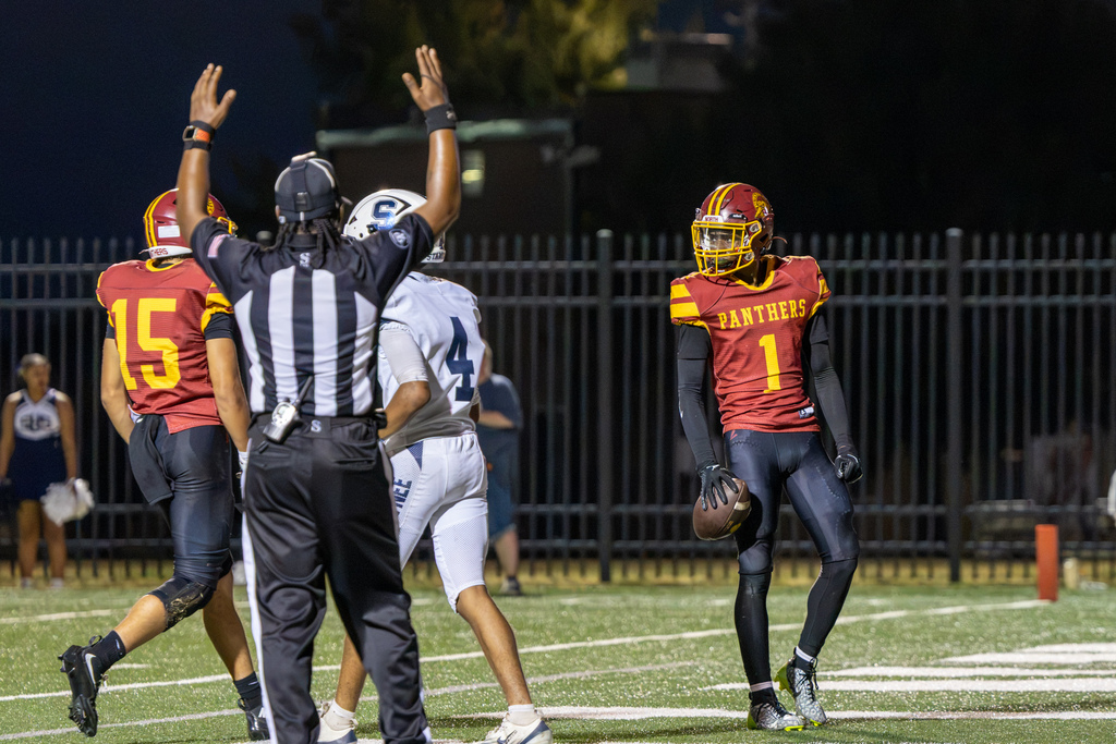 An official signals a touchdown as PC North player No. 1 stands in the end zone holding the football.