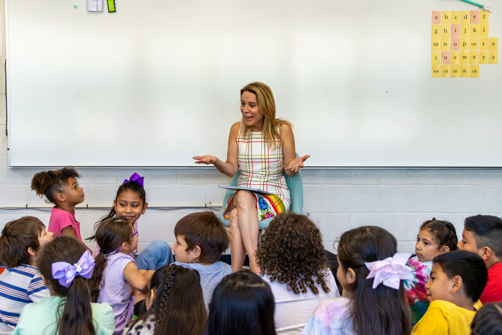 Representative Hefner smiles and gestures with both hands while talking with students seated around her at the end of the reading.