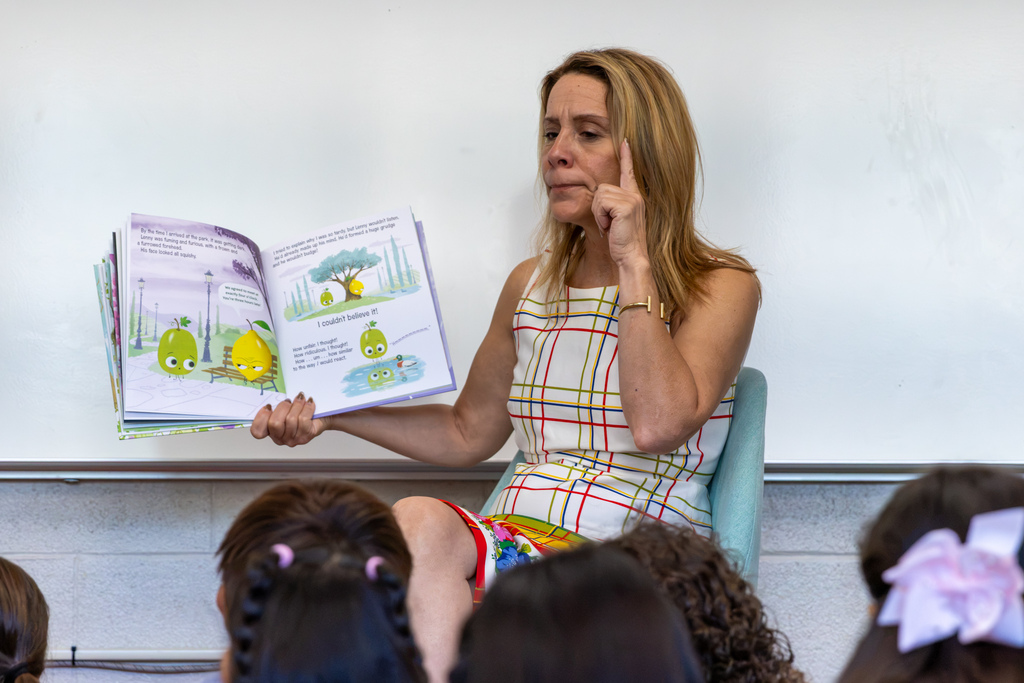 Hilldale Elementary Elementary students look up attentively at Representative Hefner as she reads, with their teacher seated in the background.