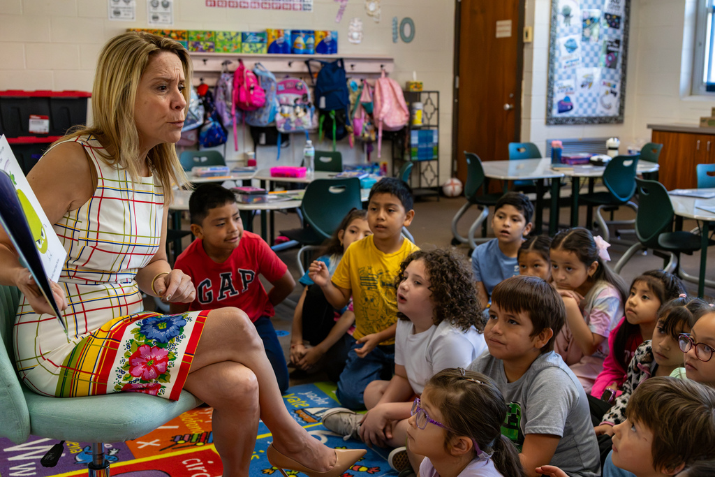 State Representative Ellyn Hefner holds open an illustrated children’s book while reading to Hilldale Elementary students seated on a classroom rug.