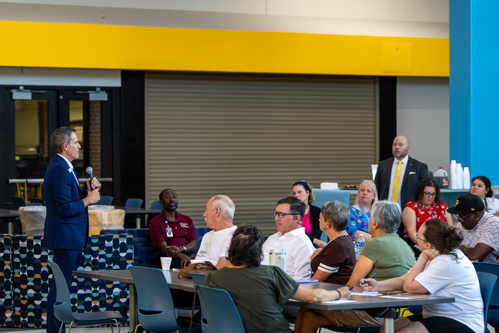 Dr. Rodrequez speaks into a microphone while seated, raising one hand as he responds during the Real Talk discussion.