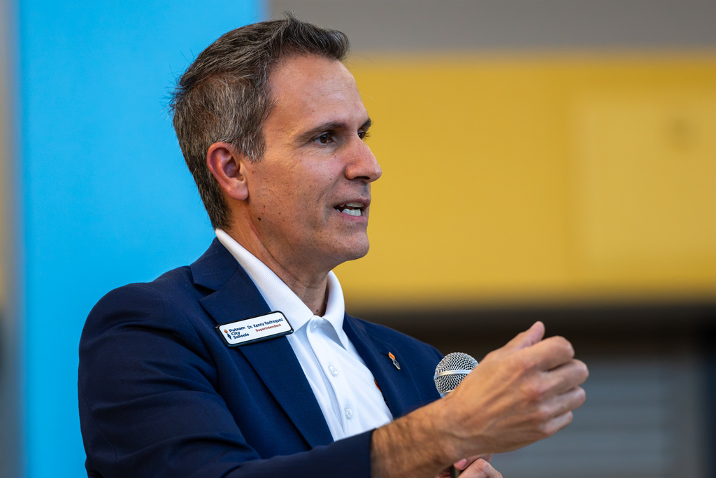 Dr. Rodrequez speaks into a handheld microphone, gesturing with one hand during the Real Talk community conversation at PC West.