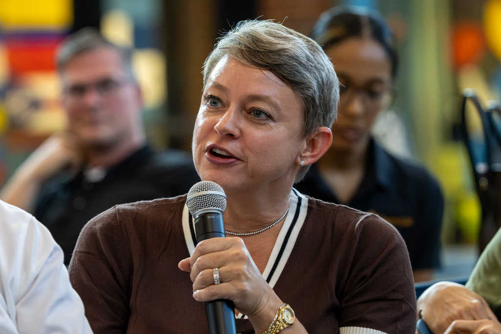A woman seated among attendees speaks into a handheld microphone during the Real Talk community discussion.