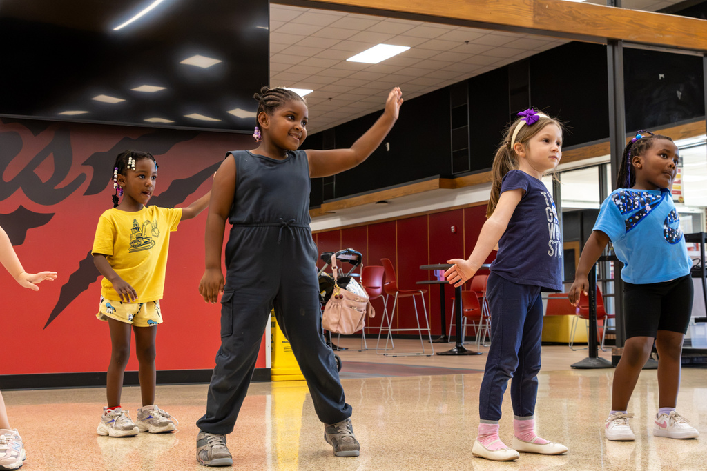 Four young dancers spread across the Commons practice a routine together, raising and extending their arms while watching for the next move.