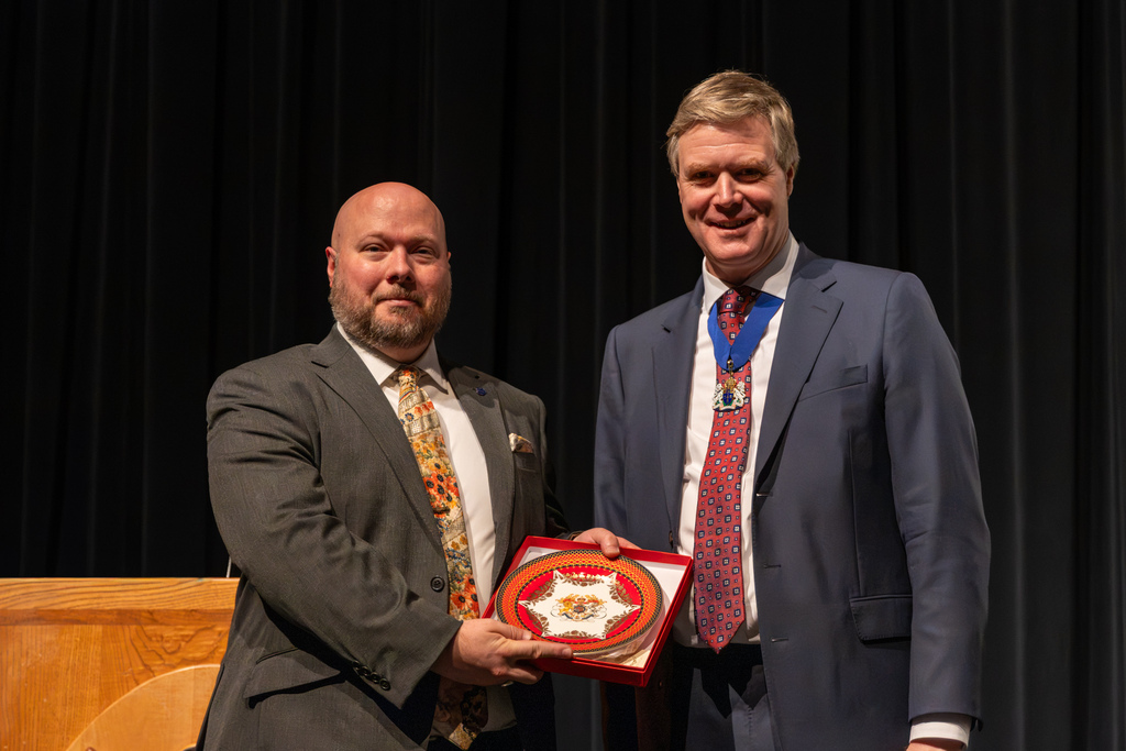 A Putnam City orchestra director and a London Springtime Music Festival representative pose together while holding a decorative plate presented as a gift from Buckingham Palace.