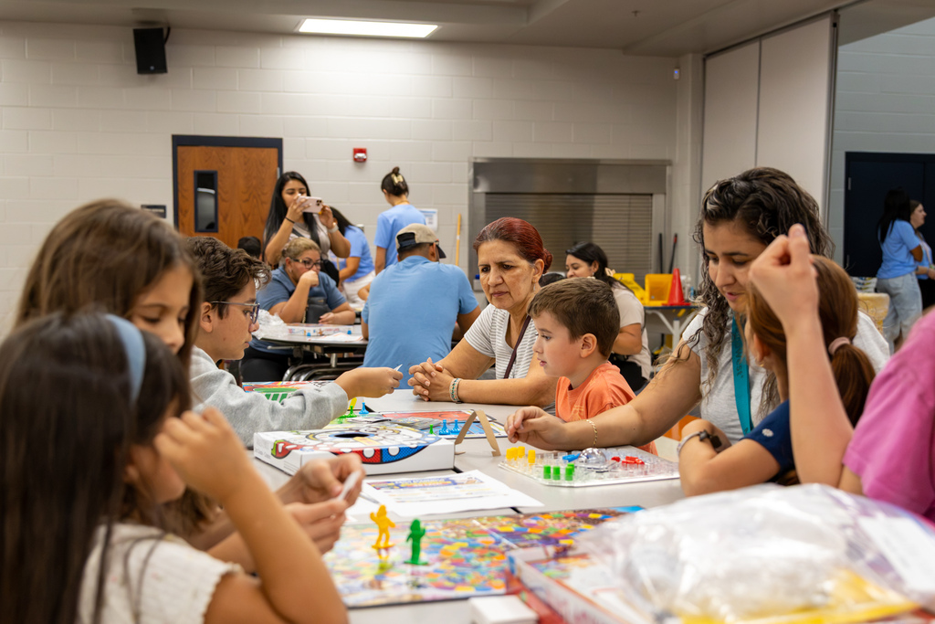 Students and family members fill the room playing board games together during Central Elementary’s Family Game Night. Several generations gather around one table in the foreground.