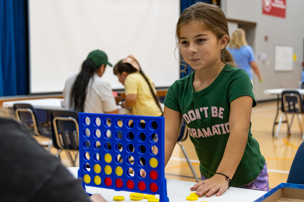 A student leans over a Connect 4 game board while playing with another person during Central Elementary’s Family Game Night.