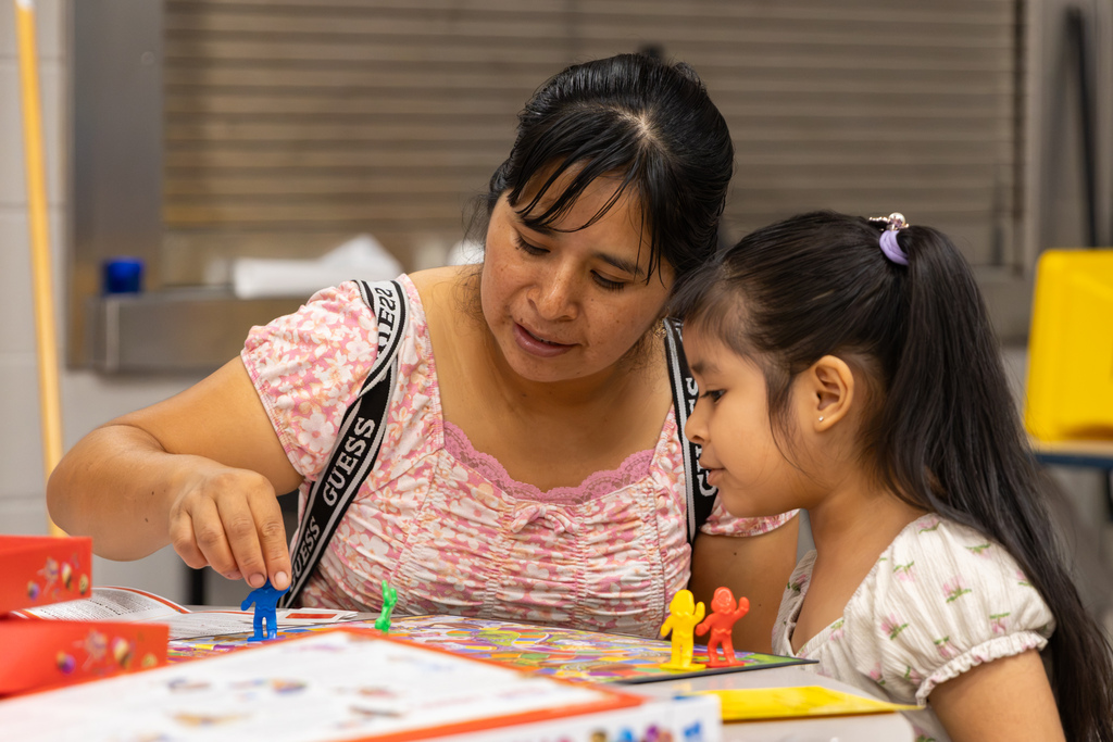 A woman and a young girl play a colorful board game together during Central Elementary’s Family Game Night, moving game pieces across the board.