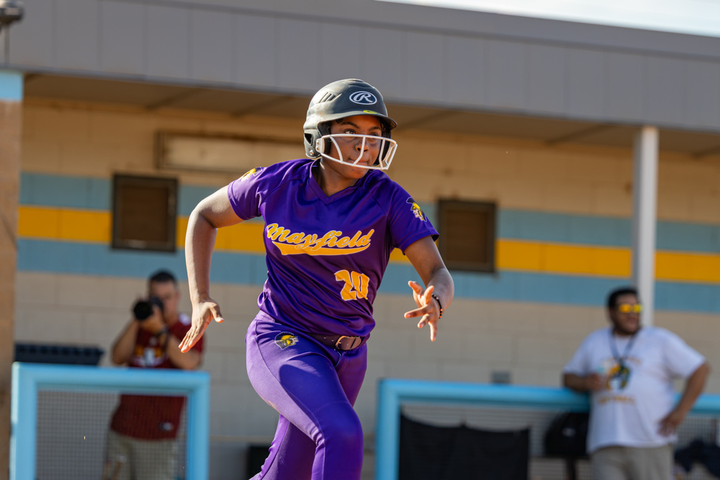 A Mayfield runner in purple accelerates toward the next base during the game.