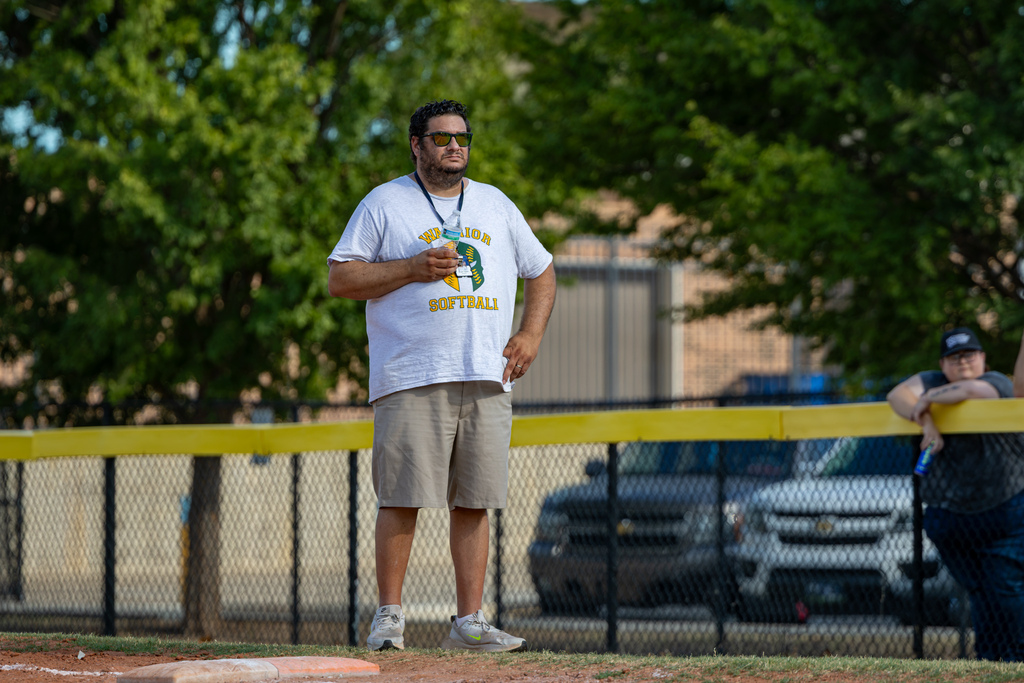 A Western Oaks Middle School softball coach stands near the field watching play during a game against Mayfield Middle School.