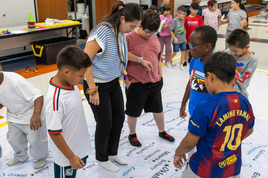 A teacher and several Central Elementary students stand on the giant Oklahoma map while discussing locations and directions during the geography lesson.