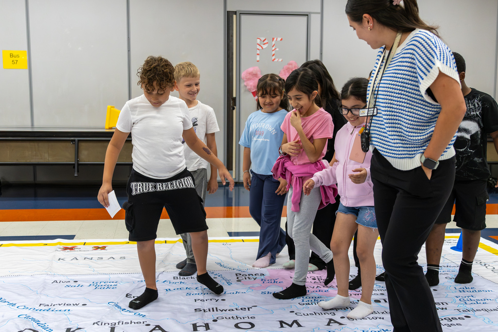 Students and a teacher walk across the giant Oklahoma map near Stillwater and other north-central Oklahoma locations during an interactive geography lesson.