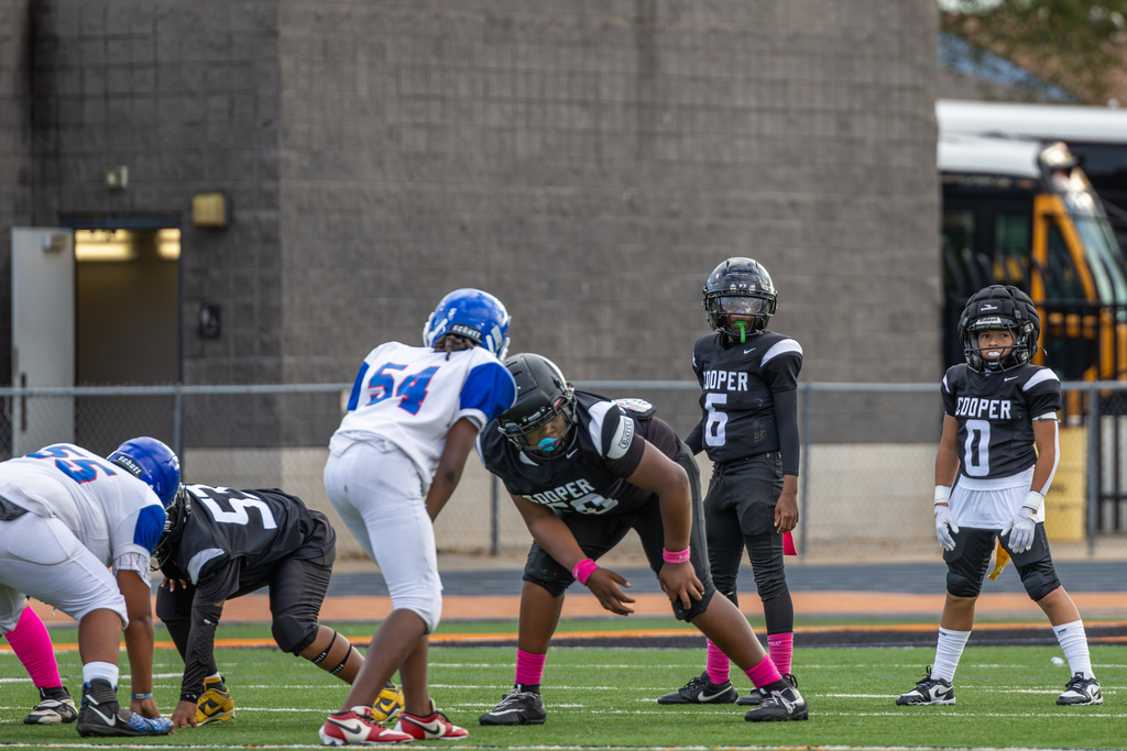 Cooper Middle School football players in black uniforms line up on offense across from Hefner players in white and blue before the snap.