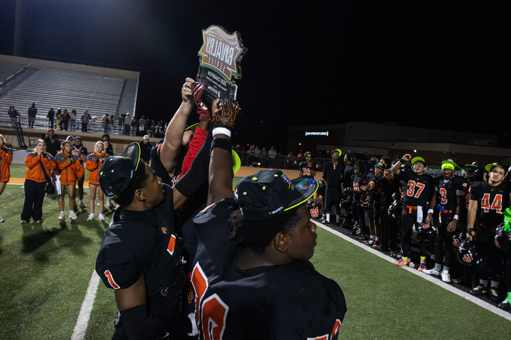 pch football players hold up great American rivalry series trophy in front of team