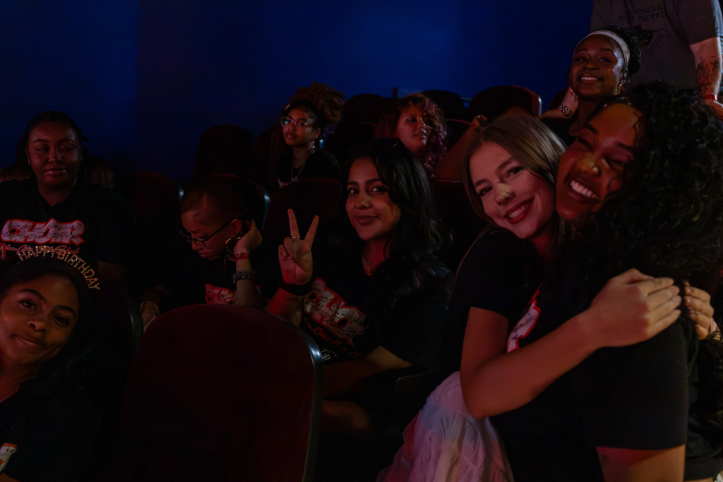 Putnam City High School choir students sit together in the concert audience, with two students smiling and hugging near the front of the photo.