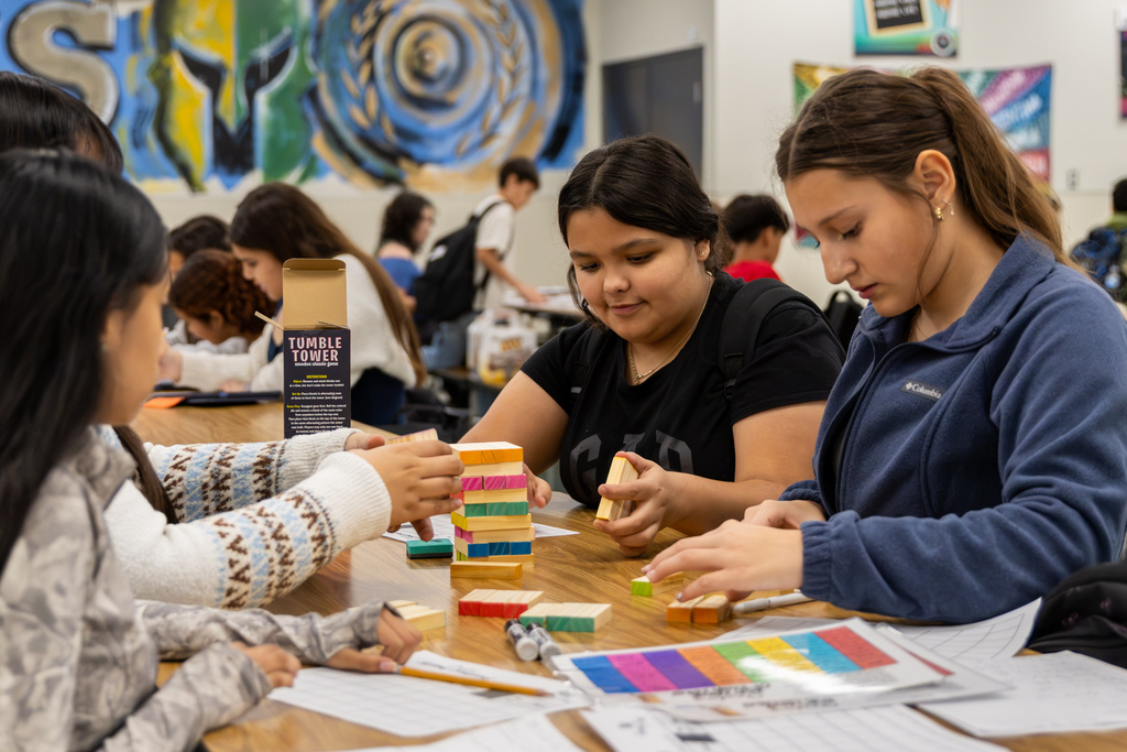 A group of Western Oaks Middle School students work together on a math activity using colorful wooden blocks and worksheets.