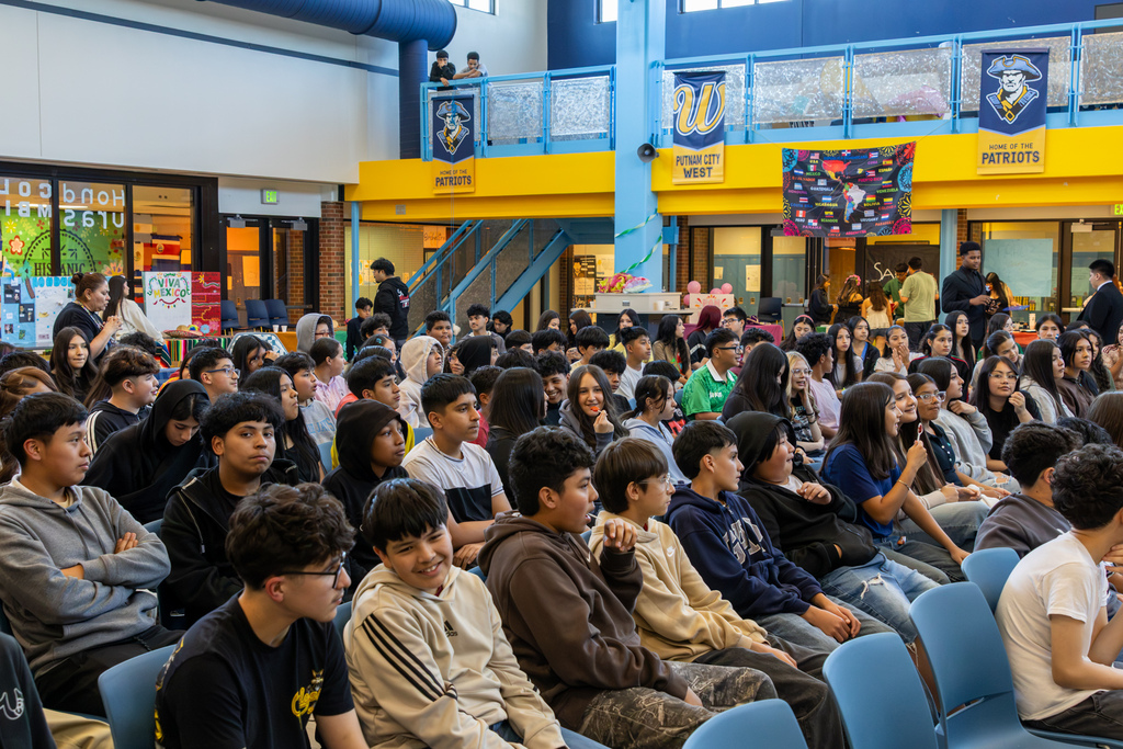 A large group of students sits together in the Putnam City West commons during the Hispanic Heritage Month Living Museum.