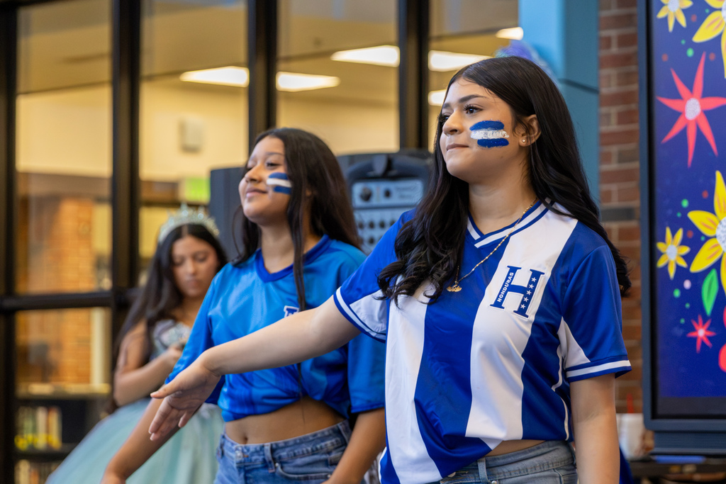 Students wearing Honduras-themed shirts and face paint participate in a cultural dance presentation.