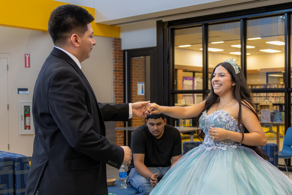 A Putnam City West student in a formal dress and tiara dances with another student during the Hispanic Heritage Month event.