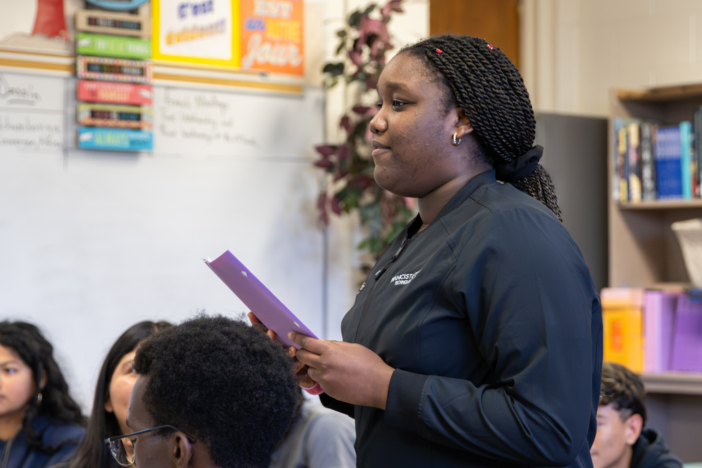 A Putnam City High student speaks from her seat while holding a purple folder during the French program presentation.