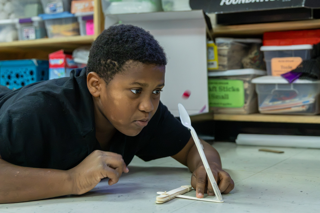 A Western Oaks Elementary student watches intently as a small red object flies through the air after launching from his handmade catapult.